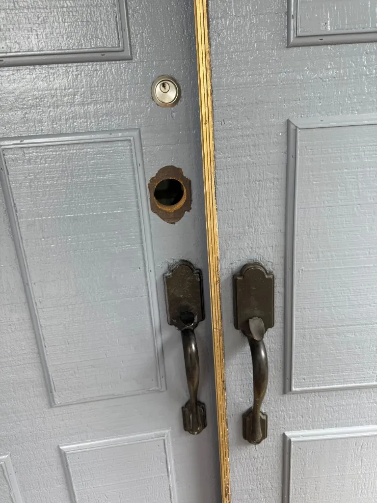 Grey double doors with open bore hole and incomplete hardware