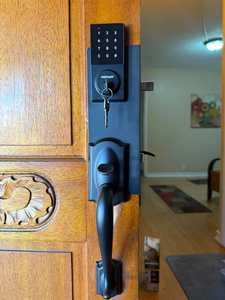Wooden entry door with new matte black Defiant smart lock and handle